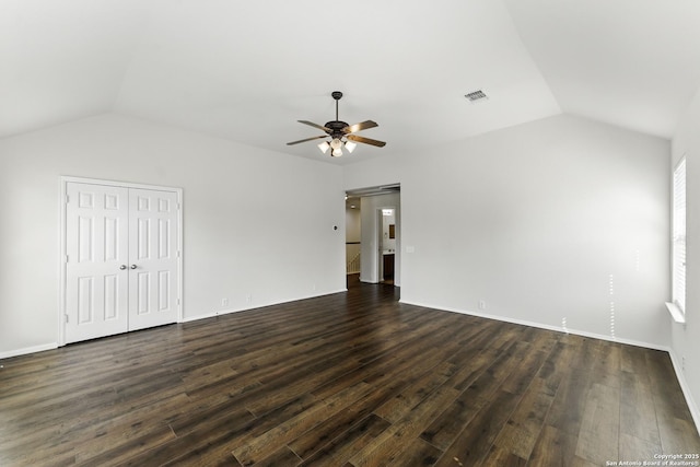 interior space featuring a ceiling fan, visible vents, dark wood-style floors, and vaulted ceiling