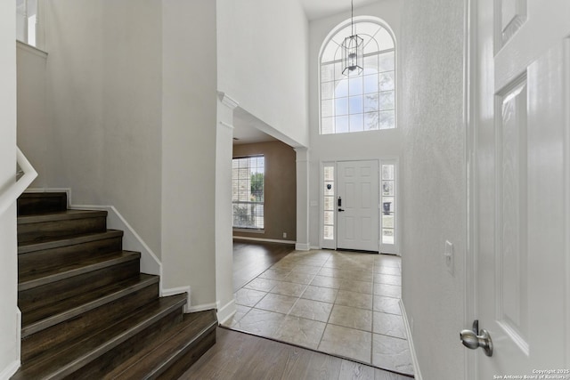 foyer entrance featuring stairs, a towering ceiling, baseboards, and wood finished floors