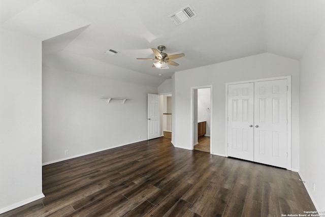unfurnished bedroom with visible vents, baseboards, a closet, dark wood-style floors, and vaulted ceiling