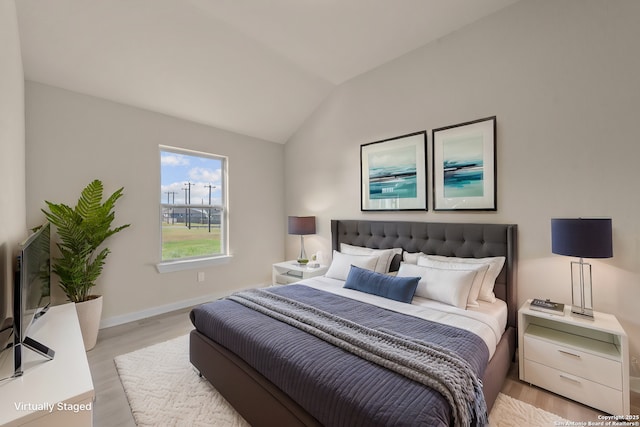 bedroom featuring vaulted ceiling, baseboards, and light wood-style floors