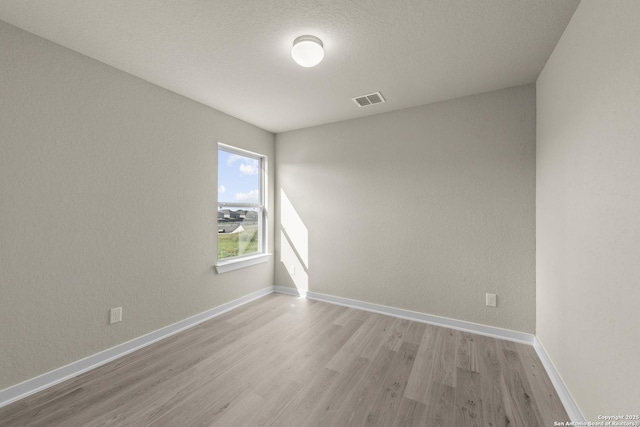 unfurnished room with baseboards, visible vents, and light wood-type flooring