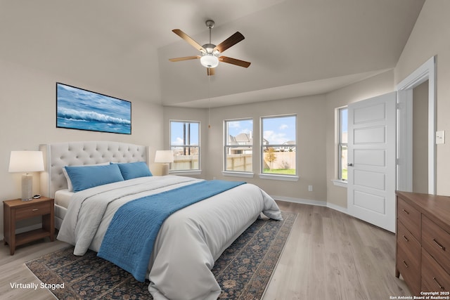 bedroom with light wood-style floors, vaulted ceiling, baseboards, and ceiling fan