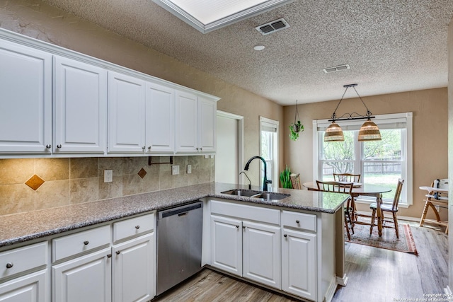 2312 Encino Xing, San Antonio, TX 78259 - kitchen featuring stainless steel dishwasher, a sink, light wood finished floors, visible vents, and a peninsula