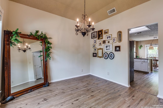 2312 Encino Xing, San Antonio, TX 78259 - unfurnished room featuring an inviting chandelier, baseboards, a textured ceiling, visible vents, and wood finished floors