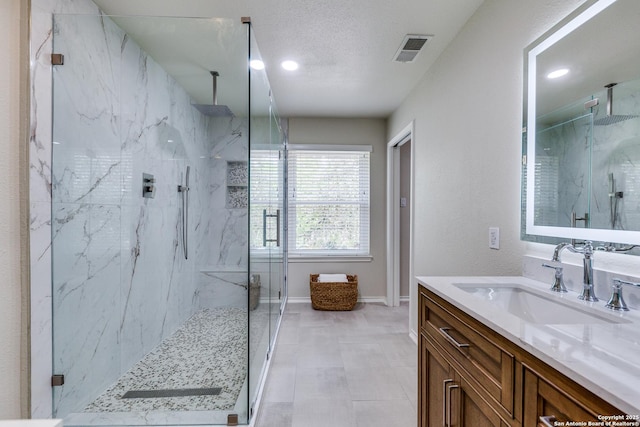 2312 Encino Xing, San Antonio, TX 78259 - full bathroom featuring a textured ceiling, visible vents, baseboards, a marble finish shower, and vanity