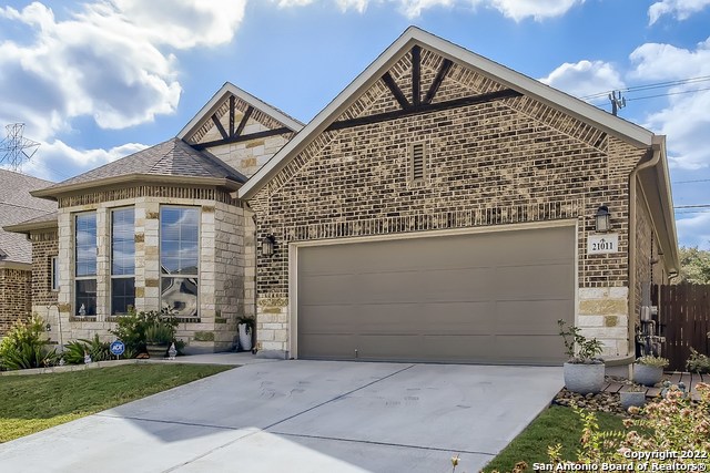 view of front facade with stone siding, brick siding, driveway, and an attached garage