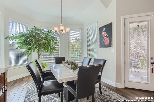 dining area featuring dark wood-style flooring, plenty of natural light, and a notable chandelier