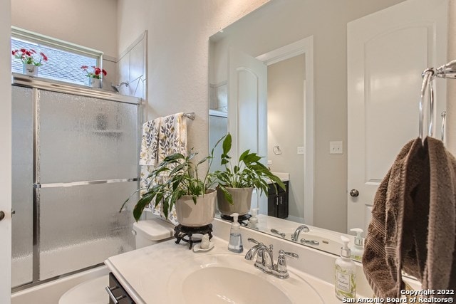 full bath with combined bath / shower with glass door, toilet, and vanity