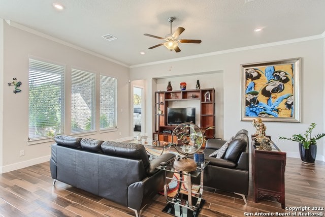 living area featuring wood finished floors, crown molding, ceiling fan, and visible vents