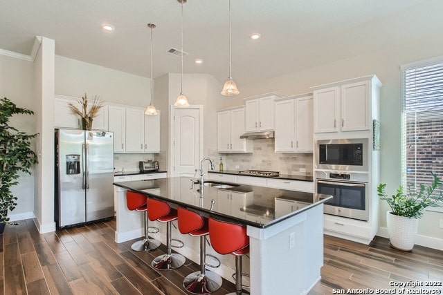 kitchen featuring tasteful backsplash, stainless steel appliances, a sink, dark countertops, and visible vents