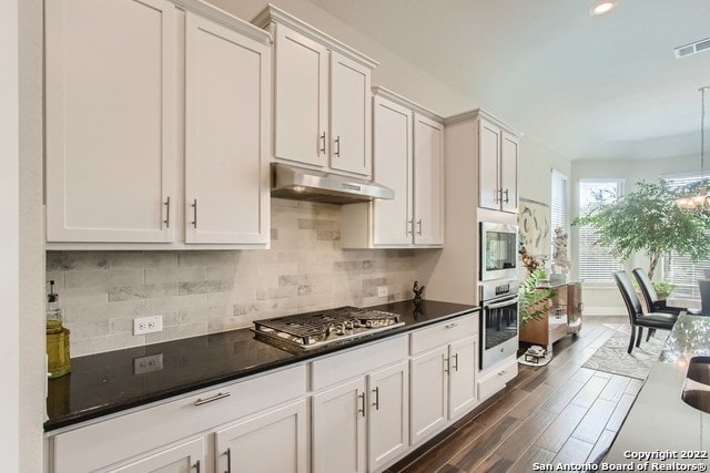 kitchen with visible vents, dark countertops, tasteful backsplash, appliances with stainless steel finishes, and under cabinet range hood
