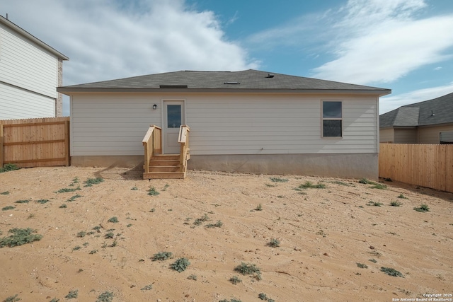 rear view of house with entry steps and a fenced backyard