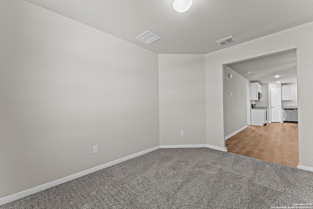 spare room featuring visible vents, baseboards, and light colored carpet