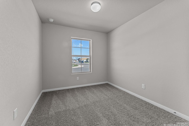 carpeted empty room featuring baseboards