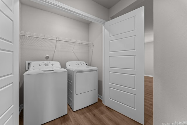 clothes washing area featuring laundry area, wood finished floors, and washer and dryer