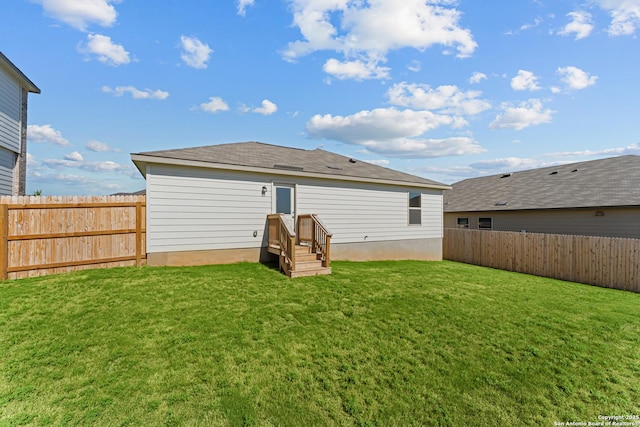rear view of property featuring a yard and a fenced backyard