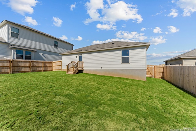 rear view of house featuring a fenced backyard and a yard