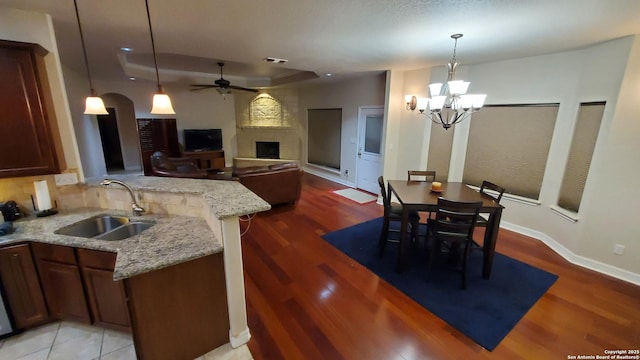 260 Campbell, Canyon Lake, TX 78133 - kitchen with light wood-style flooring, a peninsula, a fireplace, a sink, and ceiling fan with notable chandelier