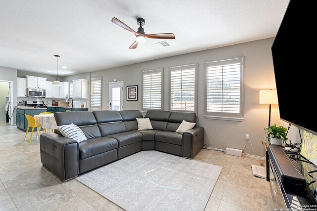 living area with visible vents, a textured ceiling, baseboards, and ceiling fan