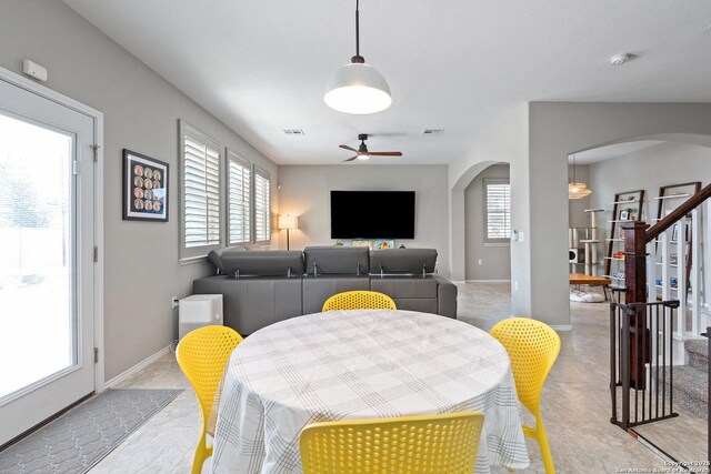dining area featuring a ceiling fan, visible vents, arched walkways, and a wealth of natural light