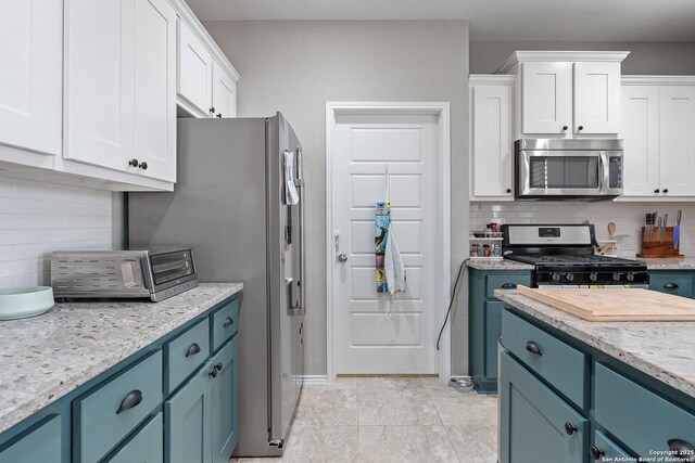 kitchen featuring decorative backsplash, white cabinetry, light tile patterned floors, and appliances with stainless steel finishes