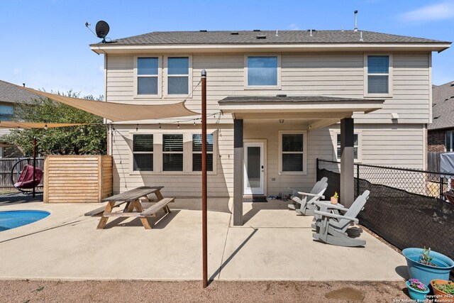 back of property with a fenced backyard, a fenced in pool, and a patio