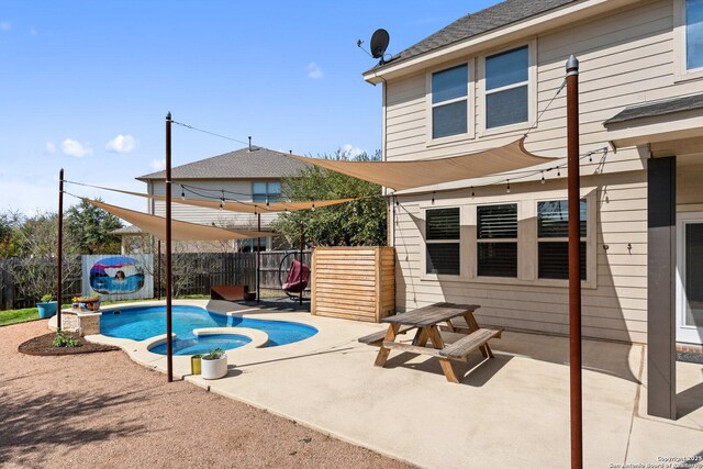 view of swimming pool featuring a pool with connected hot tub, fence, and a patio