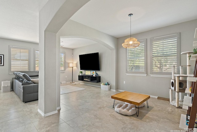 living area with arched walkways, baseboards, and tile patterned flooring