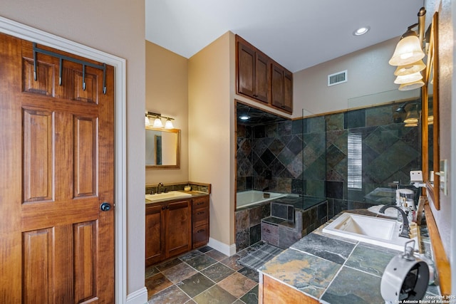 full bath with a bath, stone tile floors, visible vents, baseboards, and a walk in shower