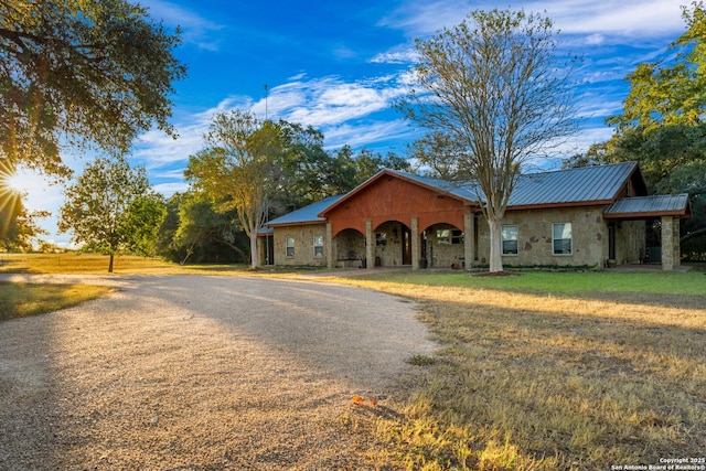 view of front of house with stone siding, a front lawn, and metal roof