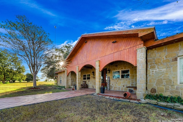 mediterranean / spanish house featuring stone siding and a front lawn