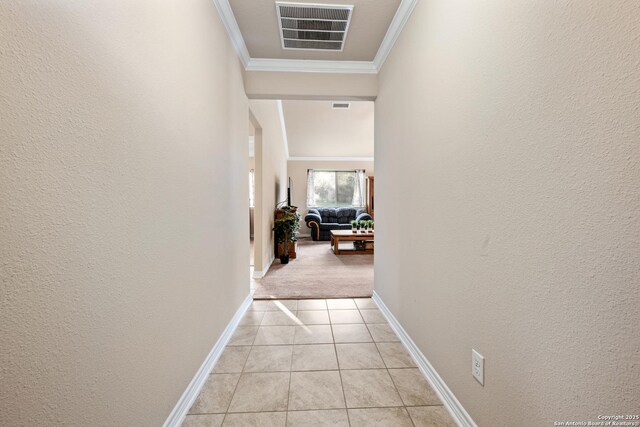 corridor featuring light tile patterned flooring, a textured wall, visible vents, and crown molding