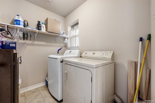 clothes washing area with light tile patterned flooring, washing machine and dryer, baseboards, and laundry area