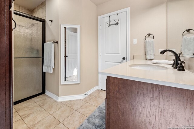 bathroom featuring baseboards, a stall shower, tile patterned flooring, and vanity
