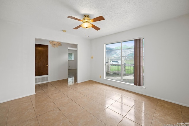 spare room with visible vents, baseboards, light tile patterned floors, ceiling fan, and a textured ceiling