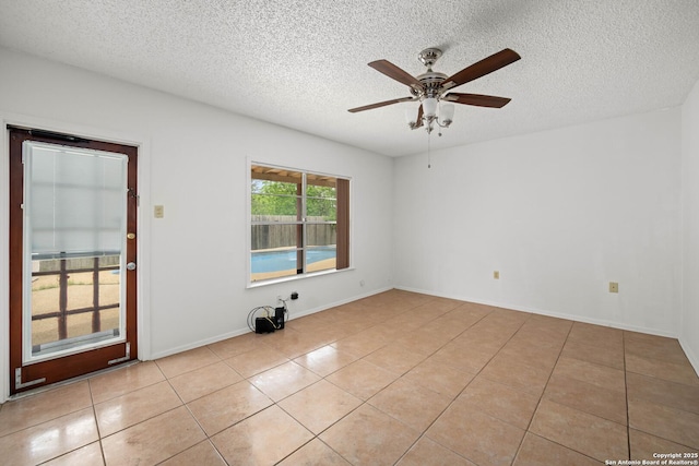 empty room featuring light tile patterned floors, a ceiling fan, and a textured ceiling