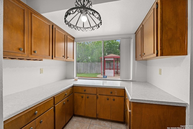 kitchen with brown cabinetry, light countertops, and light tile patterned flooring