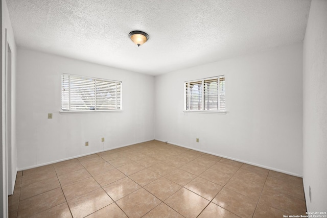 unfurnished room with light tile patterned floors, baseboards, and a textured ceiling