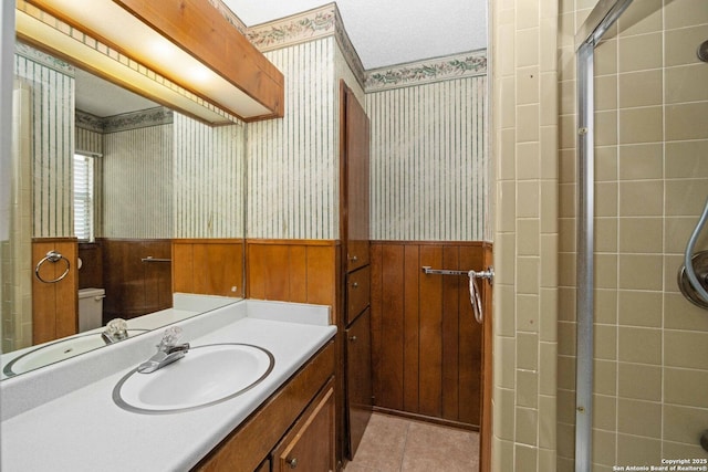 bathroom featuring wallpapered walls, vanity, wainscoting, and tile patterned flooring
