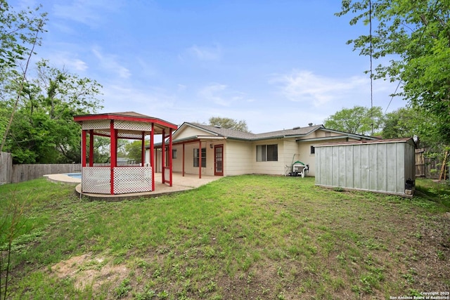 back of house with an outbuilding, a shed, a yard, a patio, and fence
