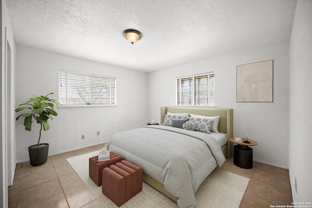 bedroom featuring a textured ceiling, baseboards, multiple windows, and tile patterned floors