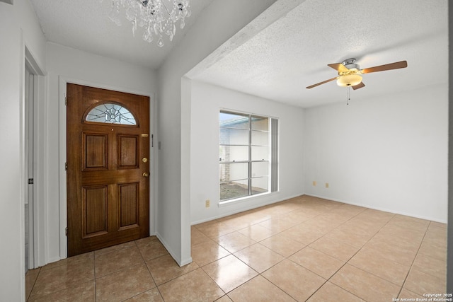 foyer with light tile patterned floors, ceiling fan with notable chandelier, and a textured ceiling