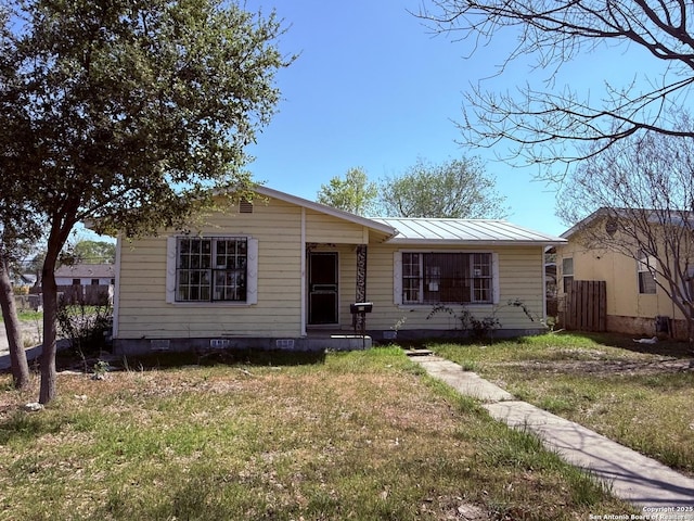 view of front of property featuring metal roof, a standing seam roof, fence, and a front lawn