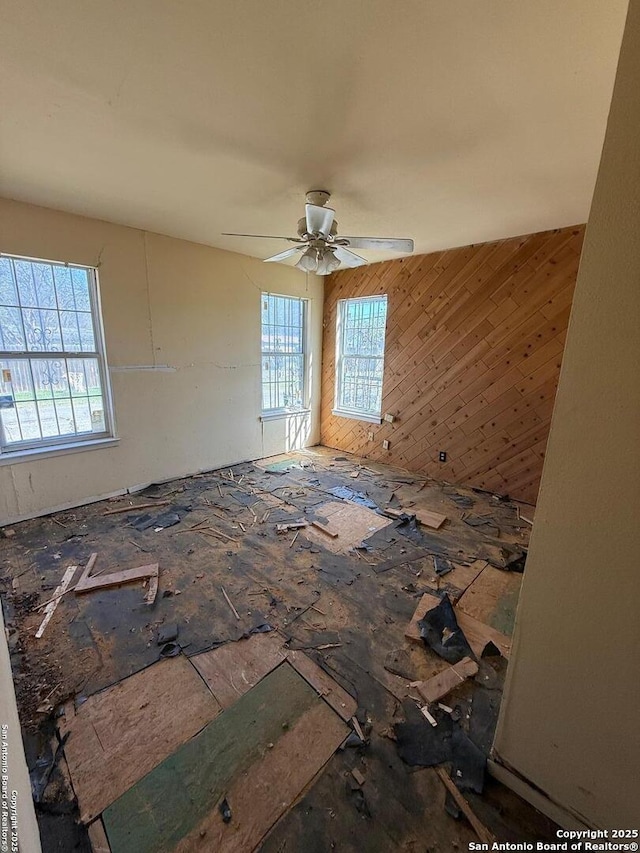 unfurnished room with ceiling fan and wood walls