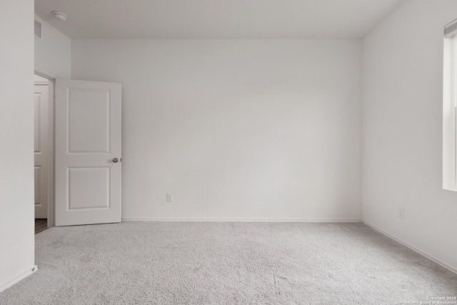spare room with carpet flooring, baseboards, and visible vents