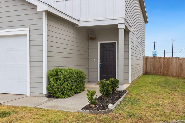 entrance to property with a lawn, fence, board and batten siding, and a garage