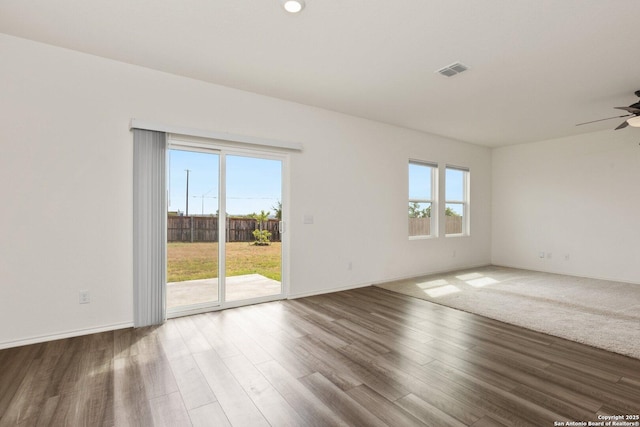 empty room with baseboards, visible vents, a ceiling fan, and wood finished floors