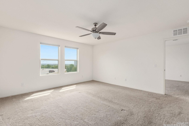 empty room with carpet floors, visible vents, and a ceiling fan