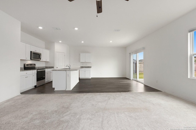 kitchen featuring open floor plan, a ceiling fan, dark carpet, and stainless steel appliances