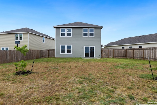 rear view of property with a fenced backyard and a yard